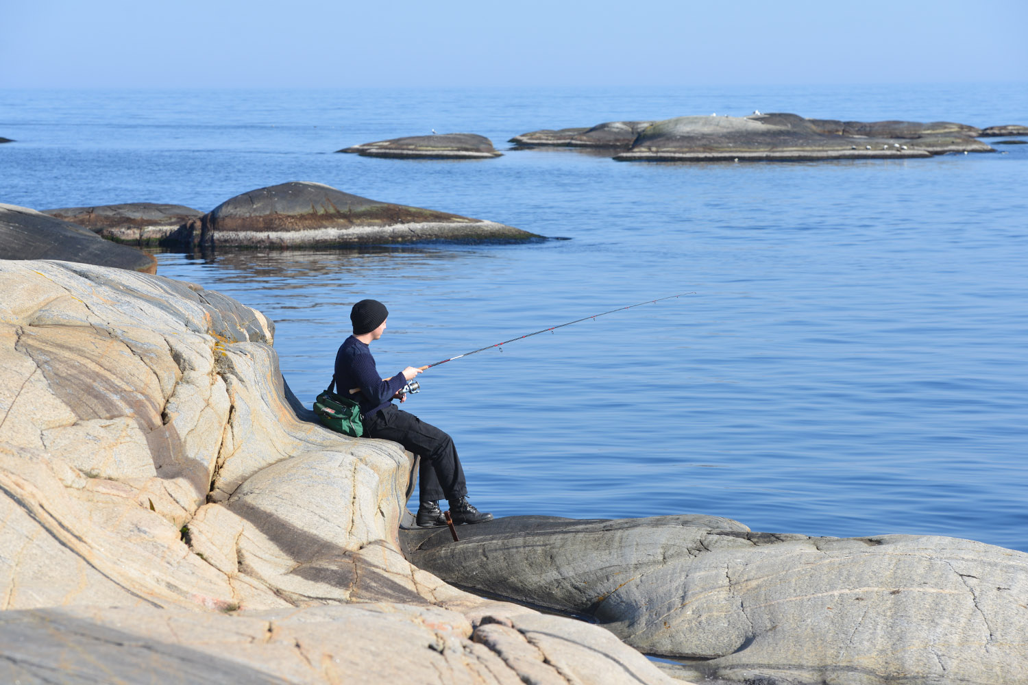Boy fishing from rocky shore.